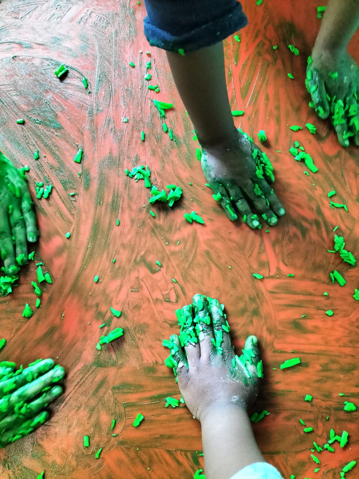 Children exploring green sensory material during a close-up messy-play activity