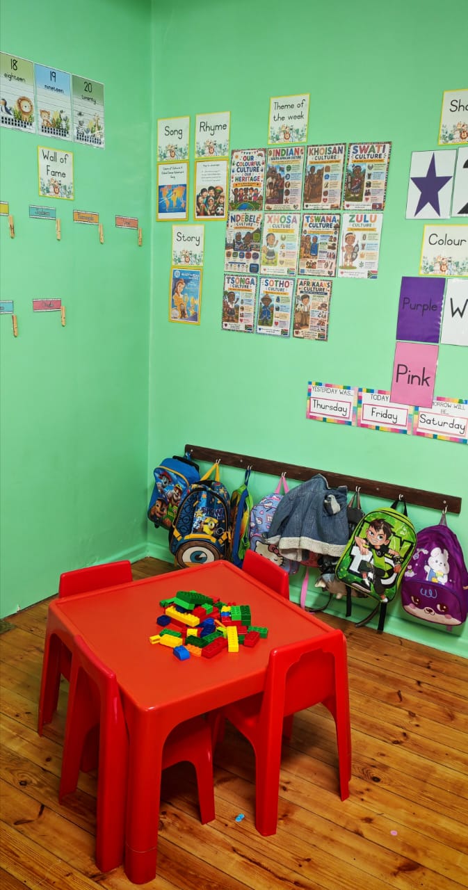 A Ladybuggz classroom with learning displays, child-sized furniture and bags stored beneath the displays