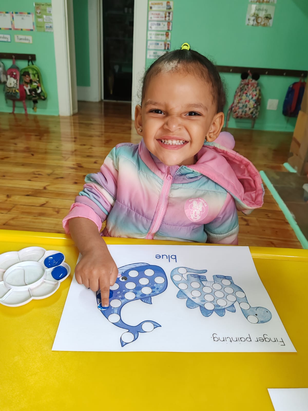 A smiling child completing a blue finger-painting activity worksheet