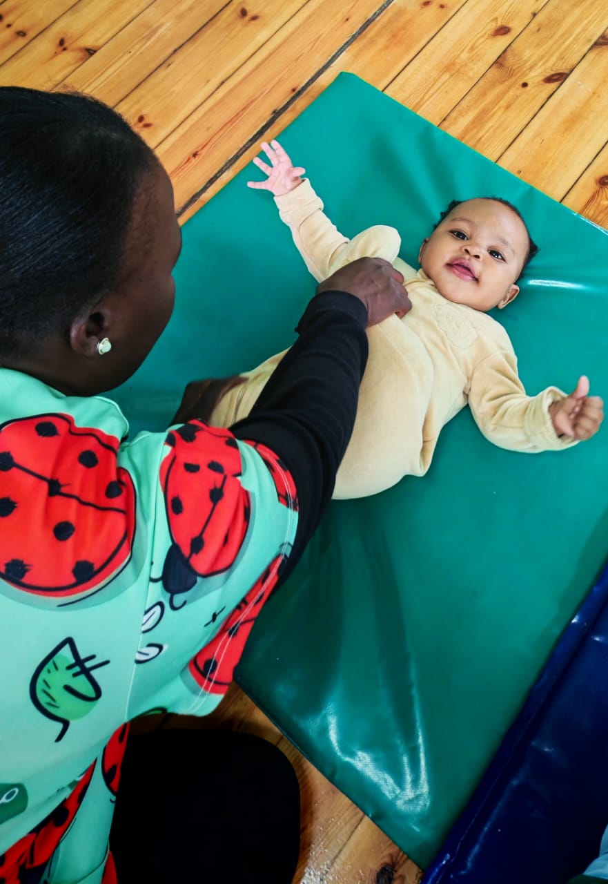 A Ladybuggz staff member guiding tummy time with a baby