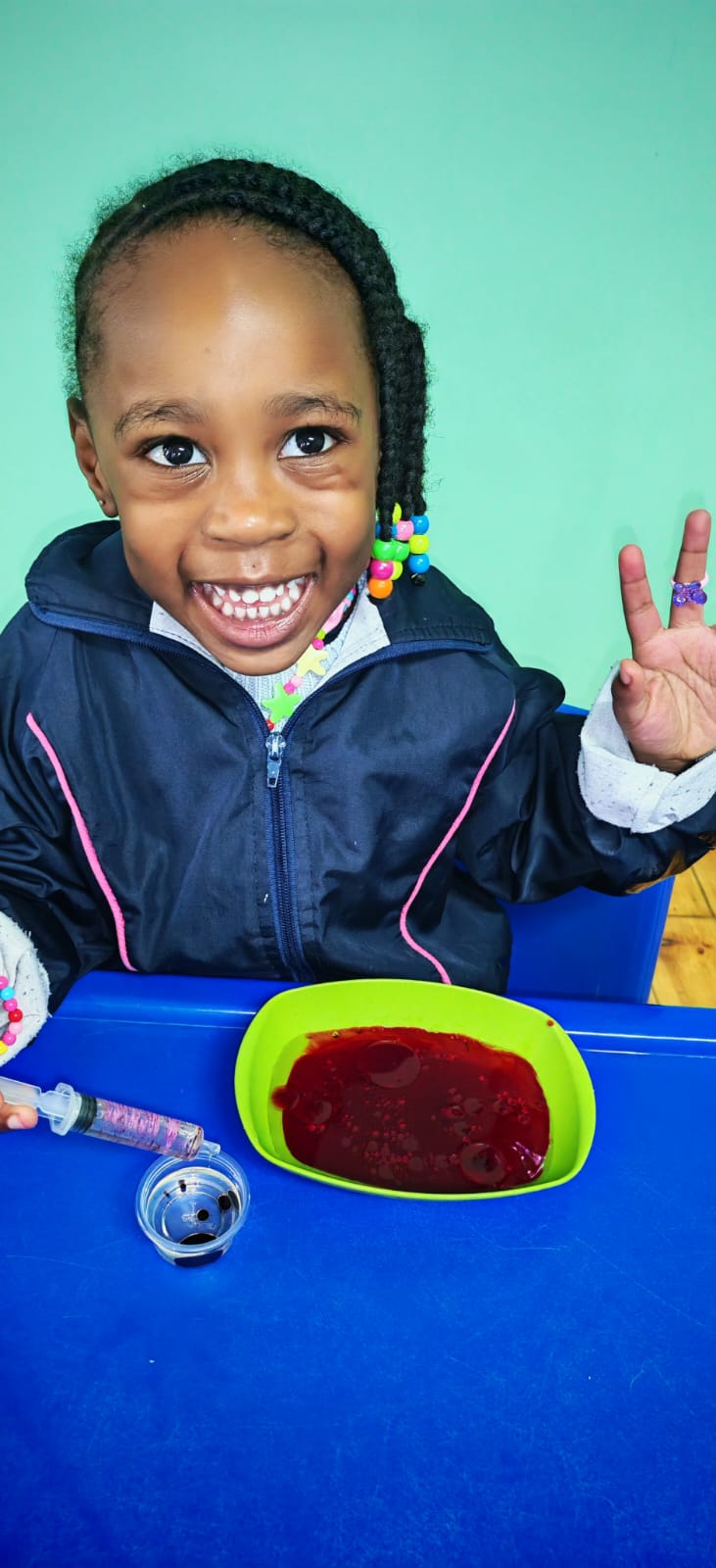 A smiling child exploring a science activity at a blue table