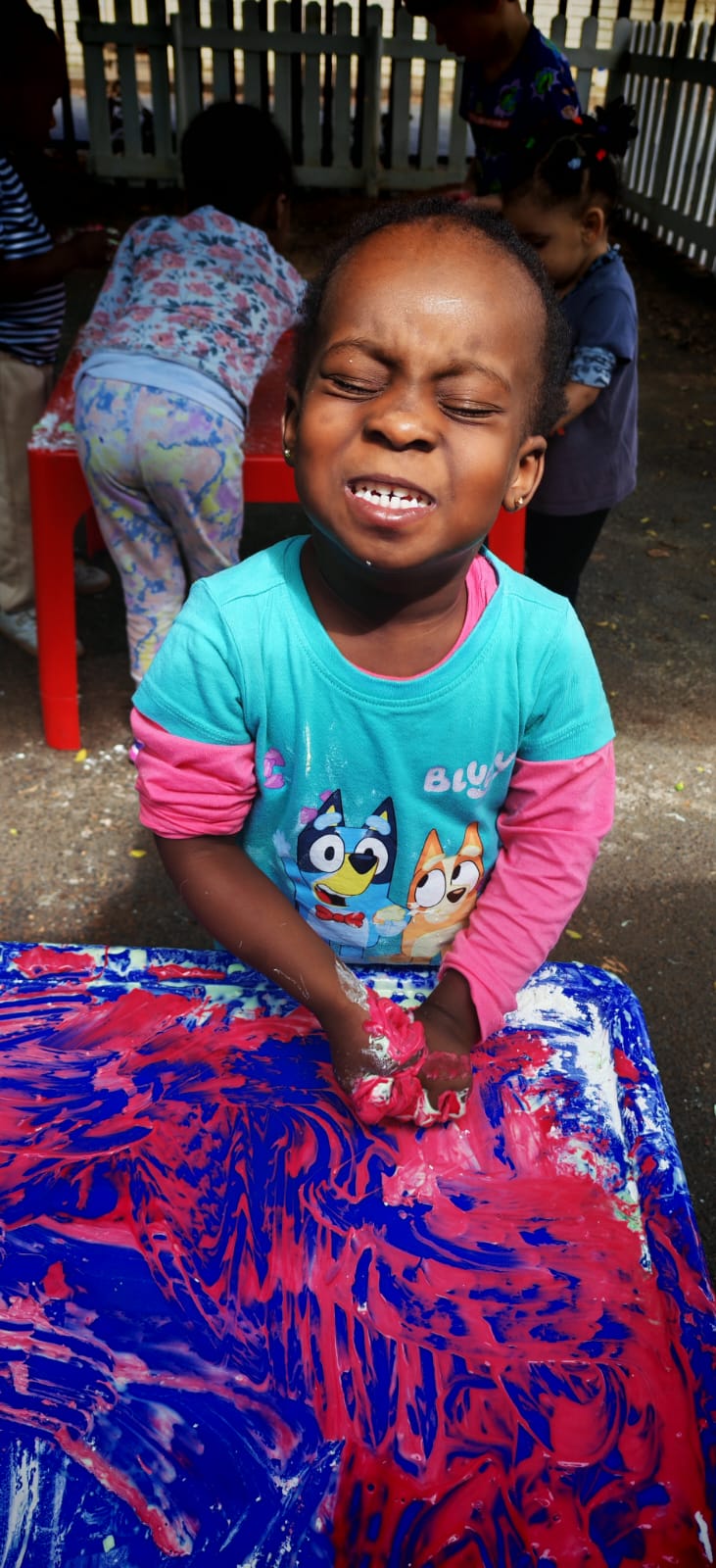 A child enjoying a colourful messy-painting activity at Ladybuggz Preschool